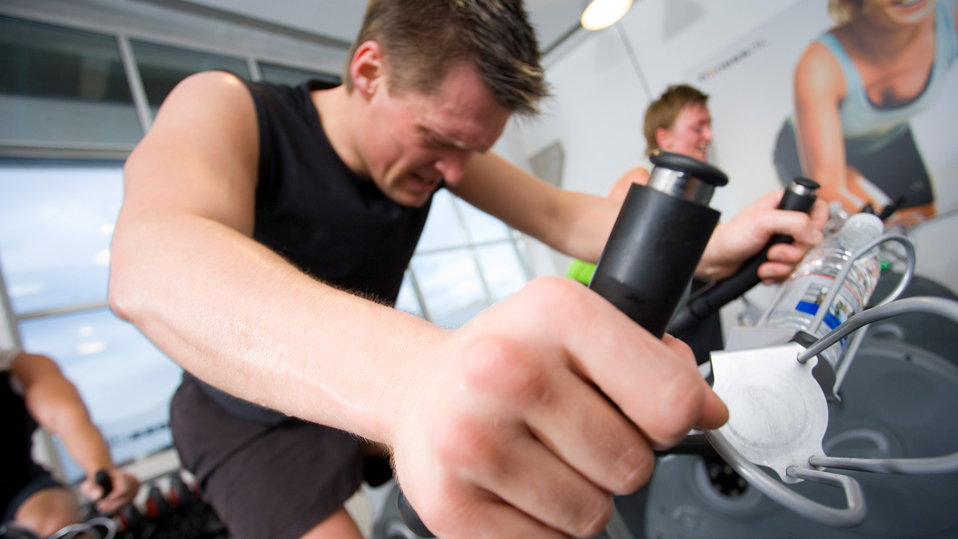 Mand sveder på motionscykel i træningslokale