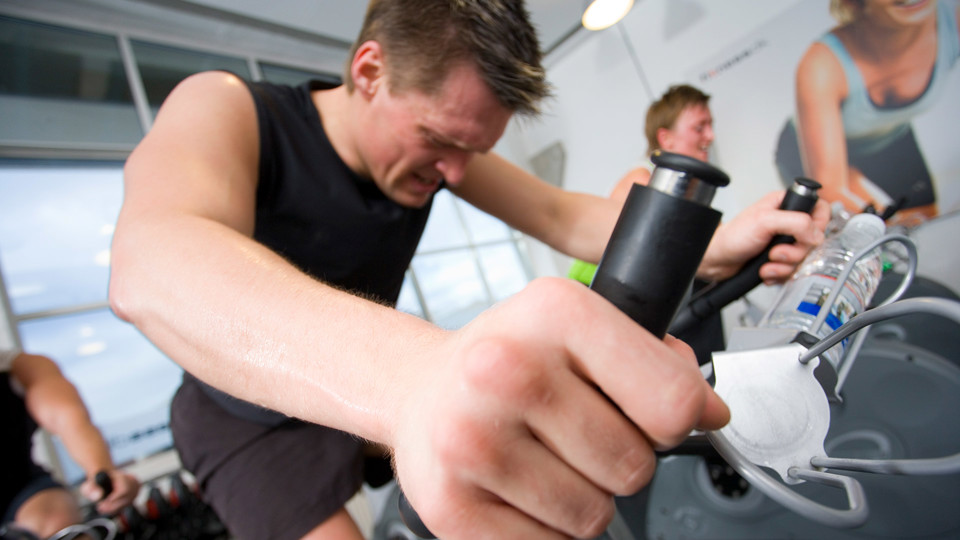 Mand sveder på motionscykel i træningslokale